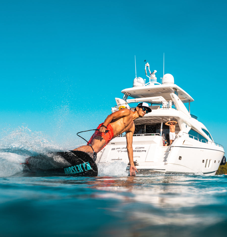 Hombre utilizando una tabla de Jetsurf a motor en fuerteventura con un barco detrás