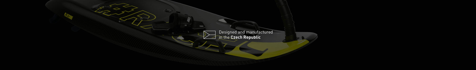 Tabla de Jetsurf negra y amarilla en primer plano, con letras que indican su diseño y manufactura en República Checa